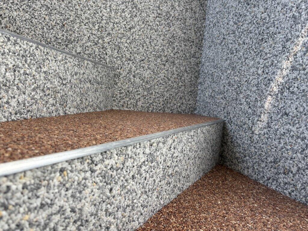 Steinteppich auf einer Treppe, Nahaufnahme der Ecke mit grauer und kupferfarbener Mischung