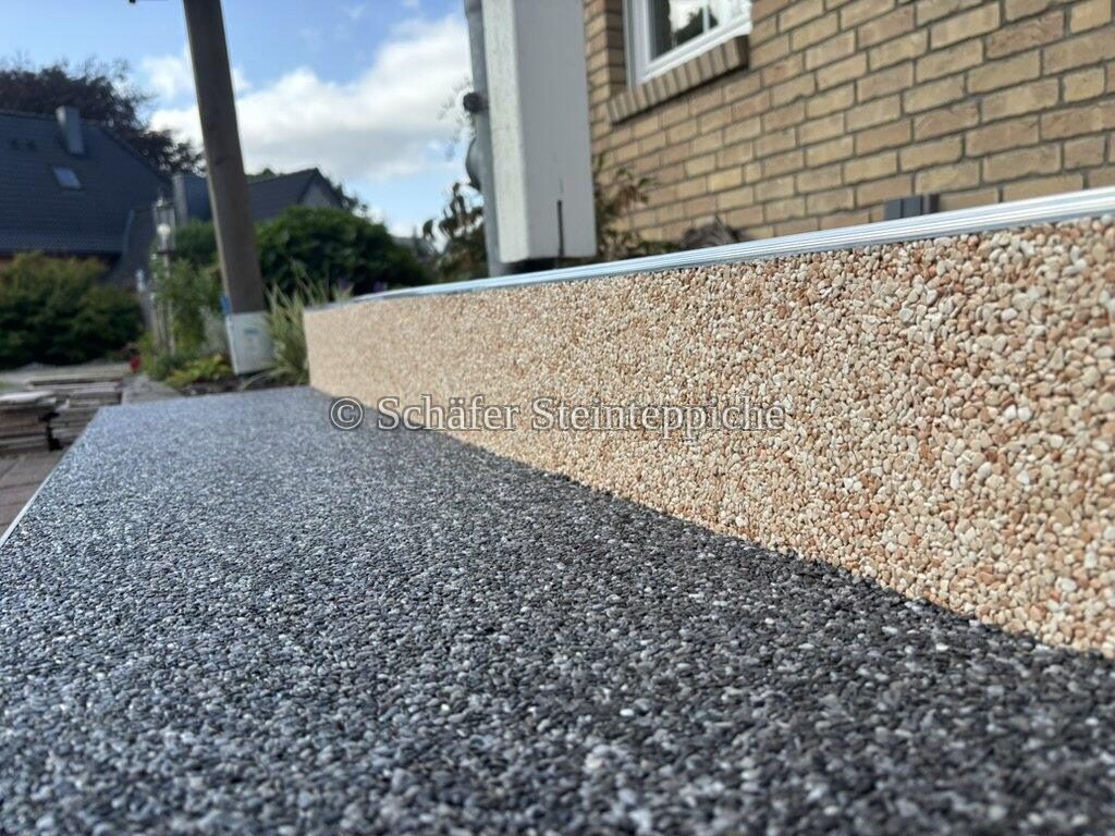 Nahaufnahme einer Mauerkante mit zweifarbigem Steinteppich im Freien